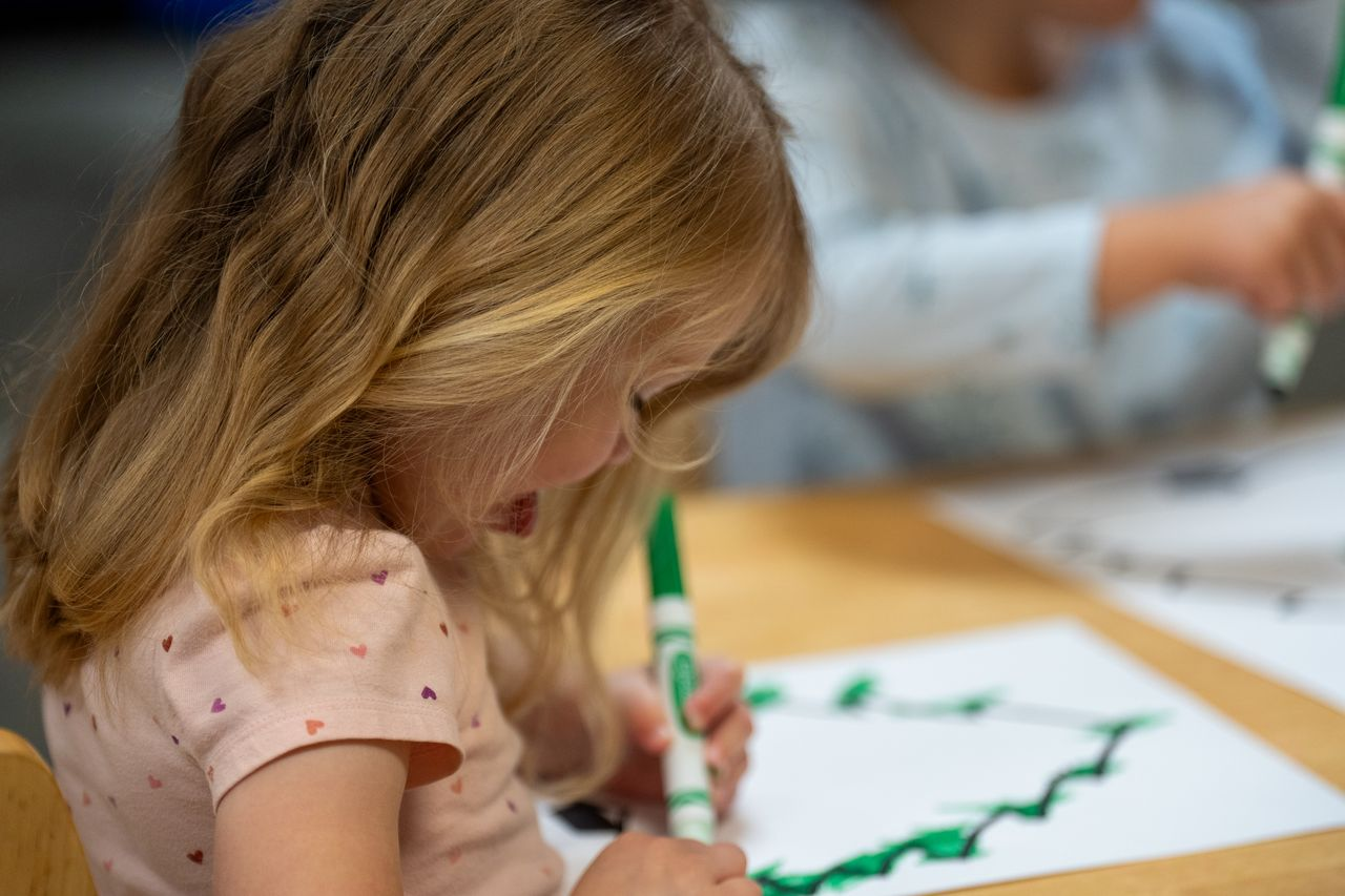 Young girl focused on drawing with a green marker